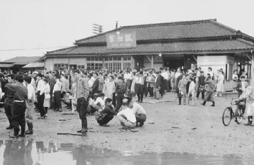 雨で不通になり駅で待つ人々