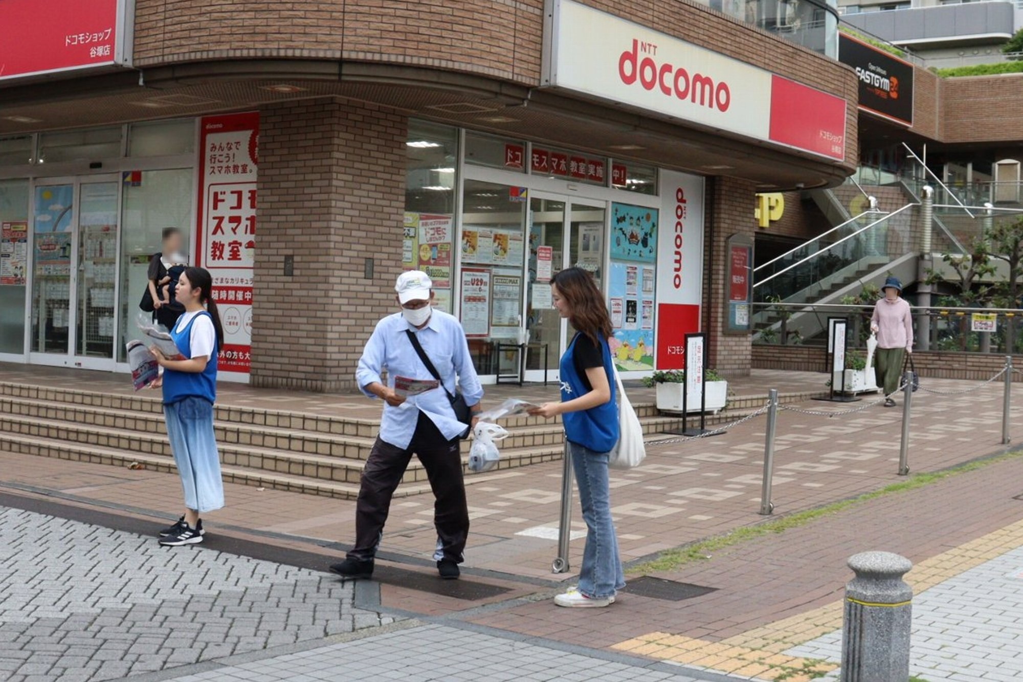 大学生から通行人へ手渡し