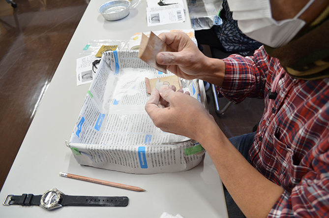 まが玉の素材を紙やすりで削っているところ。の画像